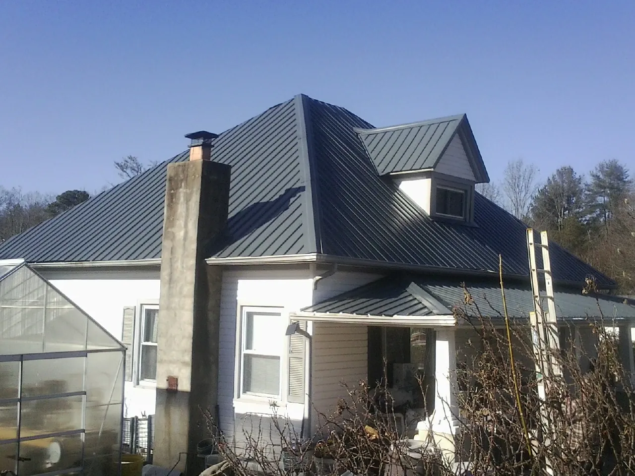 Dark blue standing seam metal roof on a white farmhouse with dormer — Slate & Tile Roof Repair by Roofing Brothers in Ellisville