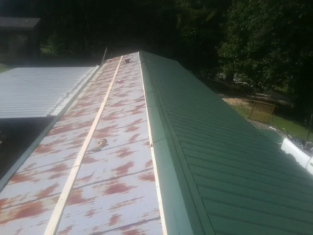 Old rusted panels beside newly installed green metal roofing — Wind Damage Roof Repair by Roofing Brothers in Ellisville