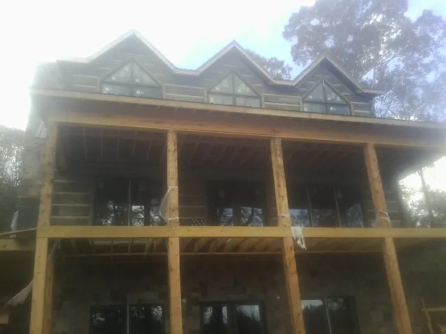 Dormers and porch framing on a large log home under construction — Roof Coating work by our crew in Ellisville