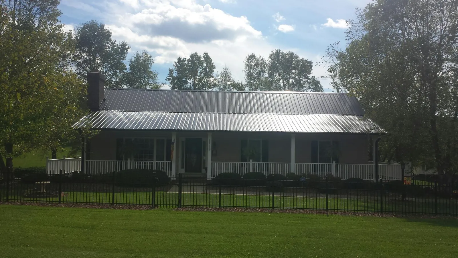 Gray metal roof on a brick ranch with a full width front porch — Gutter Guard Installation work by our crew in Ellisville