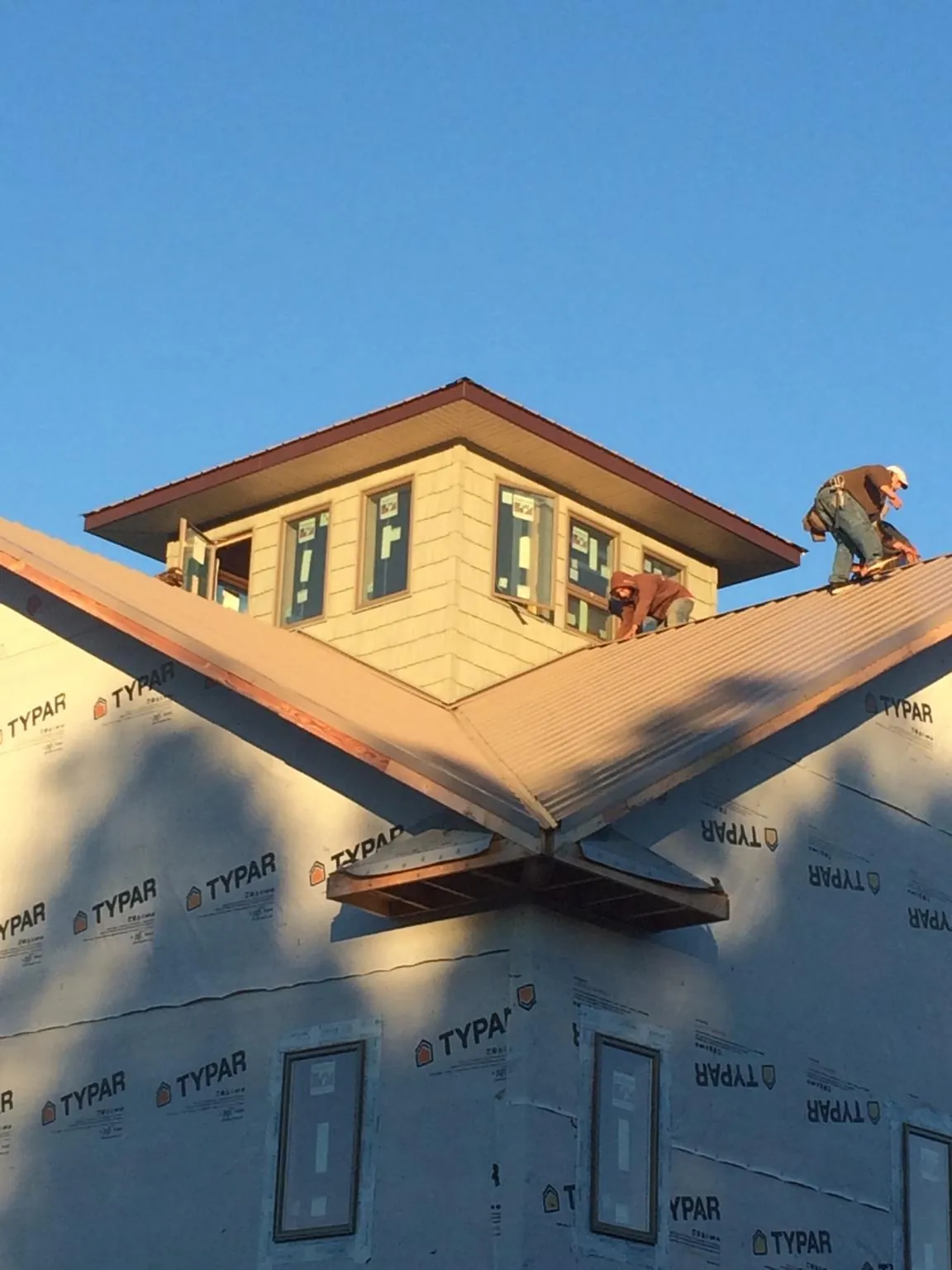 Roofers working around a rooftop cupola on a new metal roof at sunset — Roof Waterproofing in Ellisville by Roofing Brothers